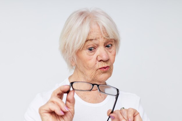 Anciana emocional en camiseta casual y gafas de fondo claro