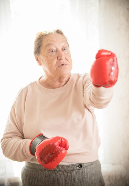 Una anciana enojada parada en guantes de boxeo