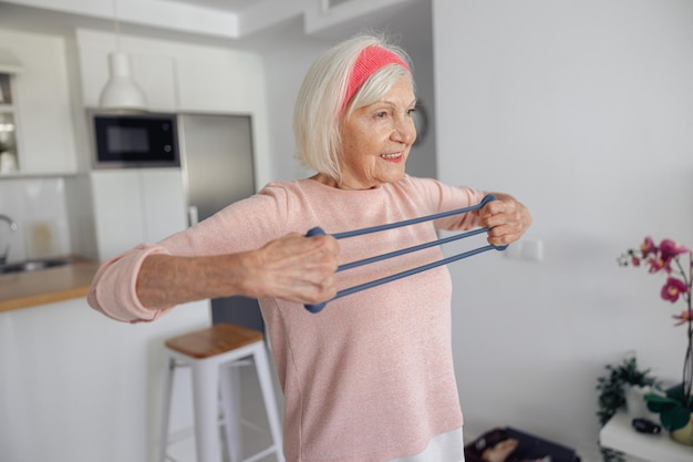 Anciana entrenando con banda de resistencia en casa