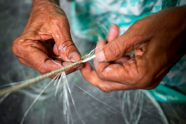 Una anciana está haciendo en sus manos flacas una cuerda de fibra de banano en Madhupur Tangail Bangladesh