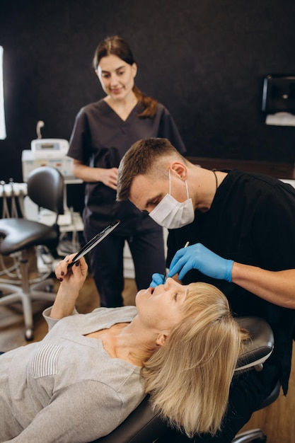 Anciana durante el examen médico con dentista masculino en el consultorio dental