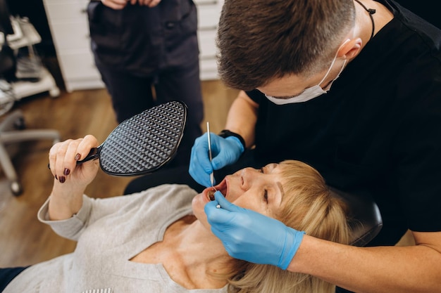 Anciana durante el examen médico con dentista masculino en el consultorio dental