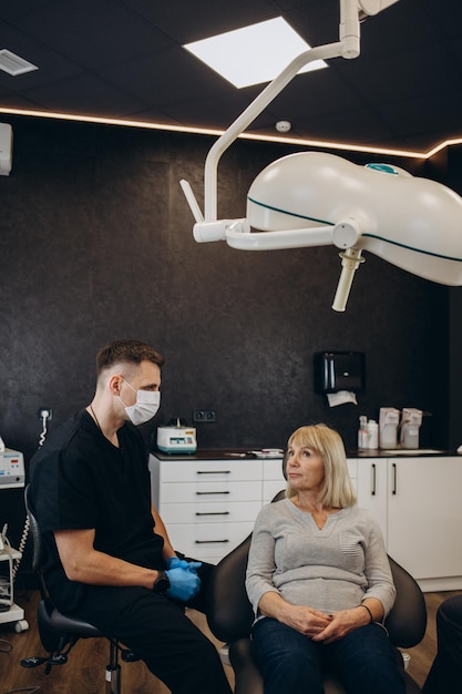 Anciana durante el examen médico con dentista masculino en el consultorio dental