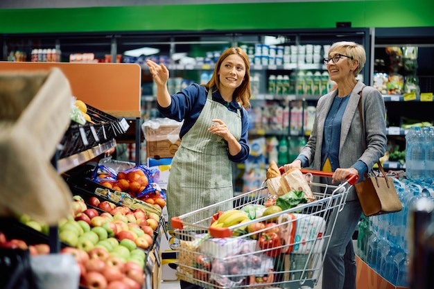 Una anciana feliz comunicándose con una trabajadora en un supermercado.