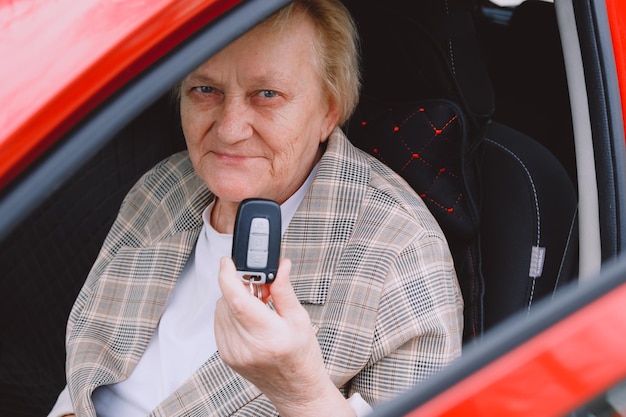 Anciana feliz de conducir un auto nuevo