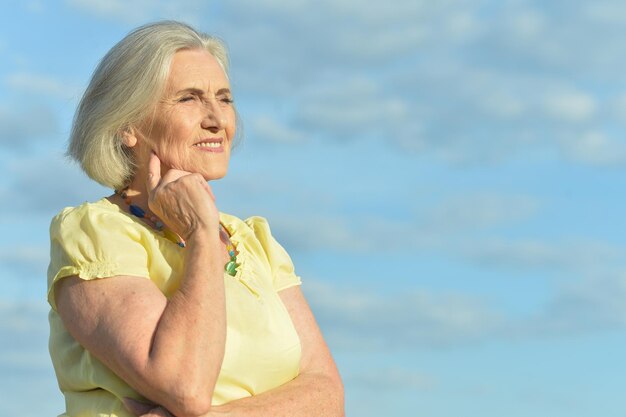 Anciana feliz posando contra el cielo azul
