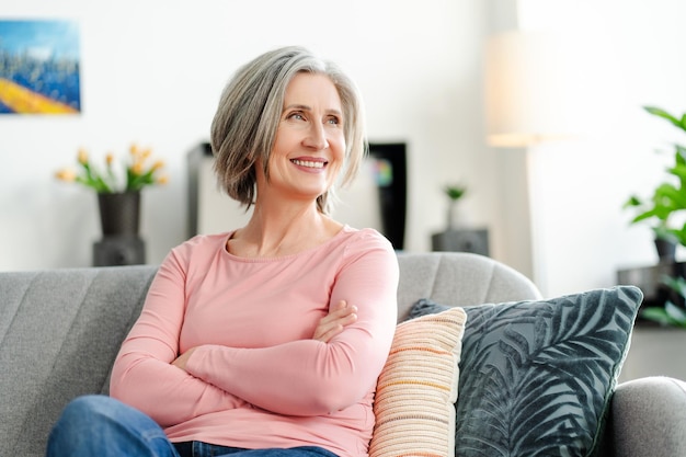 Una anciana feliz sentada en un cómodo sofá en casa belleza natural estilo de vida saludable