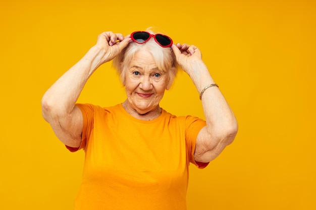Anciana con gafas oscuras en forma de corazón de fondo amarillo
