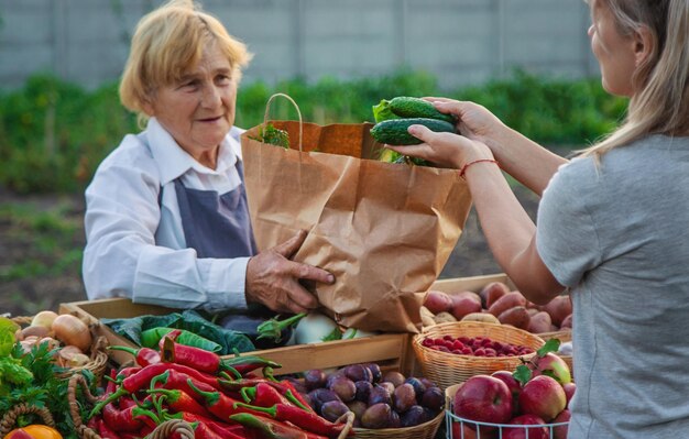 Foto una anciana granjera vende verduras y frutas en el mercado de agricultores alimentos de enfoque selectivo