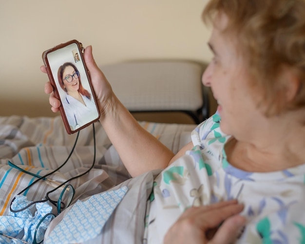 Una anciana hablando con el médico por teléfono Un jubilado sufre una enfermedad respiratoria y hace una videollamada al terapeuta Consulta en línea