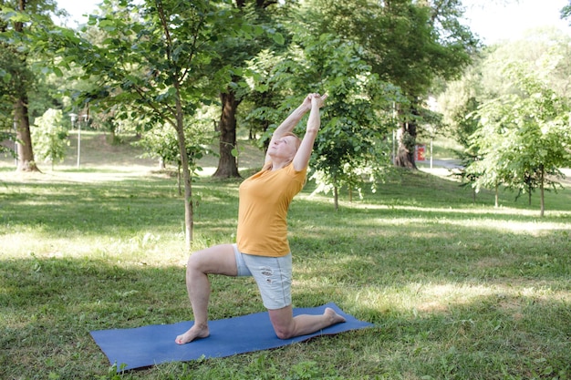 Una anciana hace yoga en el parque para realizar estiramientos para mantener el equilibrio y el equilibrio.