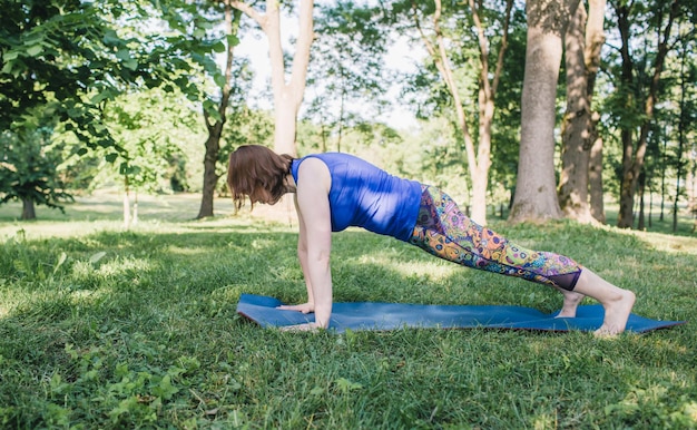 Una anciana hace yoga en el parque sobre una colchoneta Realiza complejos ejercicios de Asana lleva una vida saludable