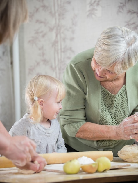 Una anciana haciendo pequeños pasteles de manzana con una niña