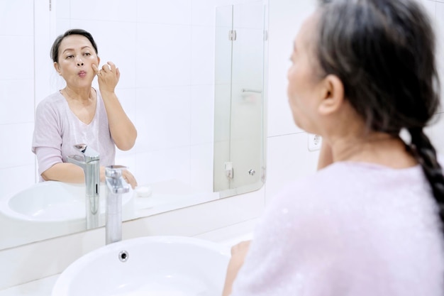 Anciana haciendo tratamiento de la piel de la cara en casa