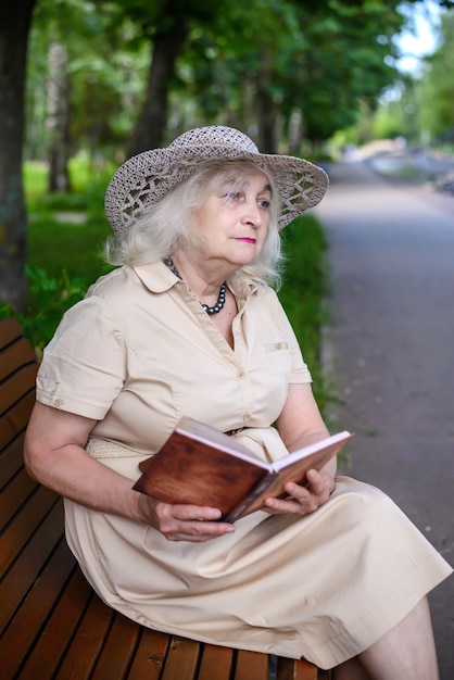 Una anciana lee un libro en el parque.