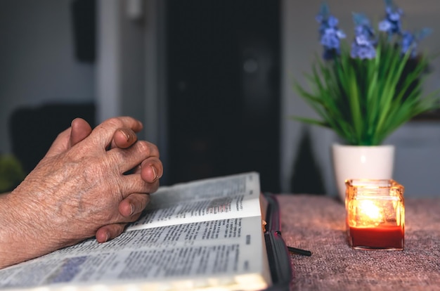 Una anciana lee las manos de la Biblia de cerca