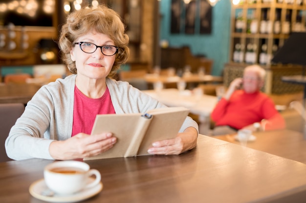 Anciana leyendo un libro en un café