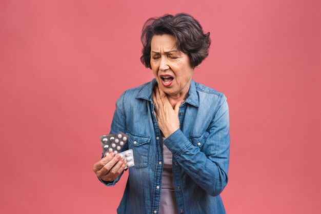 Una anciana madura sostiene su mano cerca de la garganta dolor de garganta problemas de salud