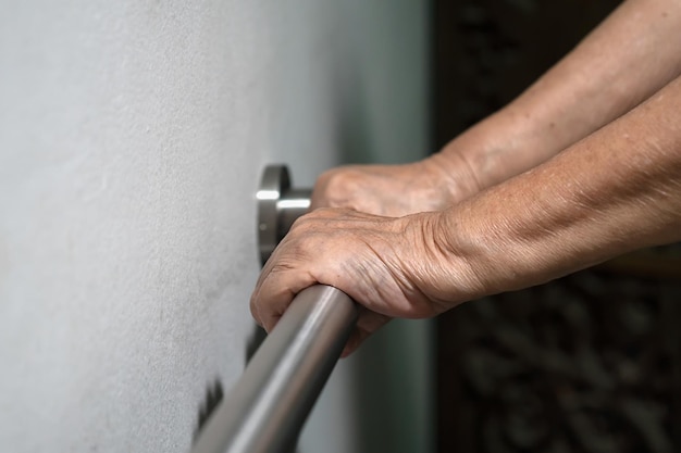 Anciana mano sujetando el pasamanos para caminar de apoyo