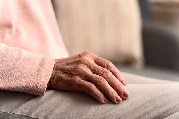 Anciana manos arrugadas acostadas sobre las rodillas cerca Anciana sentada en casa Concepto de personas jubiladas Foto de stock