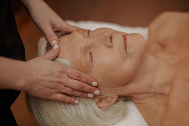 Una anciana con un masaje facial en un salón de belleza