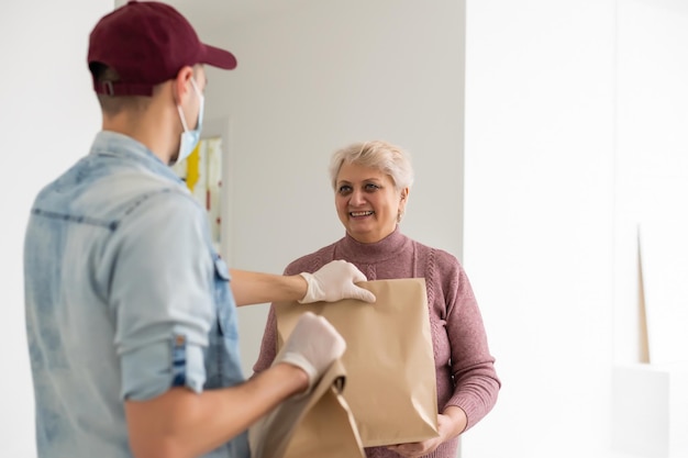 Foto una anciana con una máscara médica se queda en casa. entrega de alimentos a personas de la tercera edad.