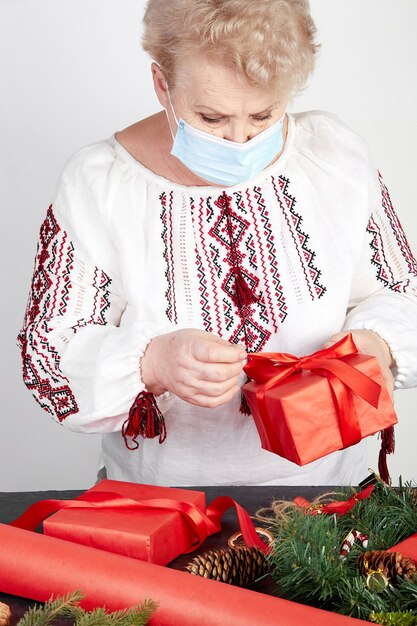 anciana con una máscara médica sosteniendo un regalo de navidad