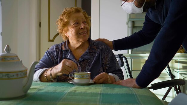 Anciana sin mascarilla porque está vacunada recibe visita de un joven con mascarilla