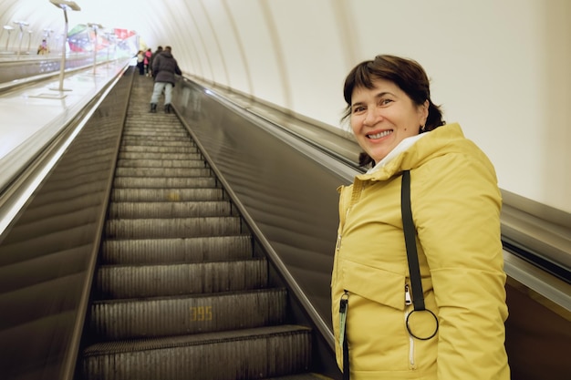 Una anciana morena con chaqueta sube las escaleras mecánicas del metro