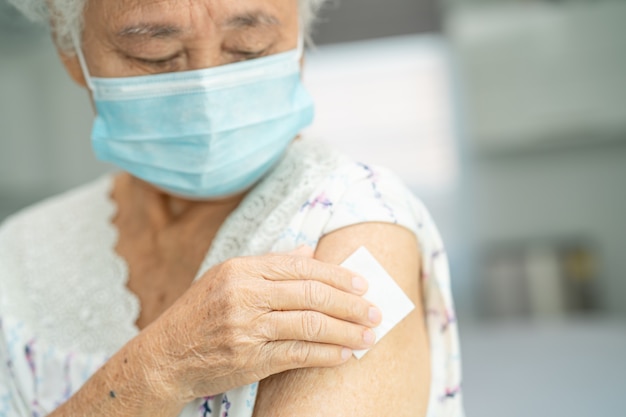 Anciana mujer mayor asiática con mascarilla recibiendo la vacuna covid19 o coronavirus