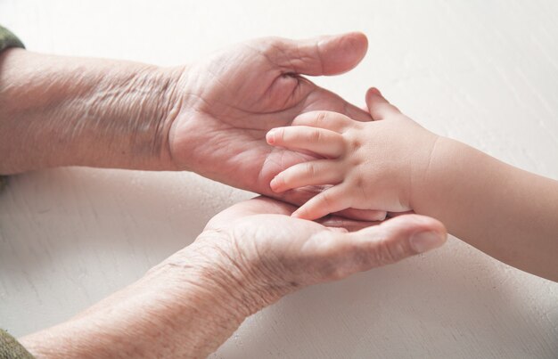 Anciana y un niño manos juntas.