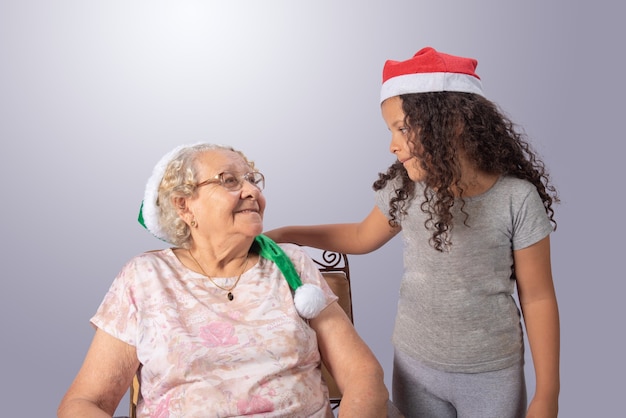 Anciana y niño con sombrero de Navidad en gris