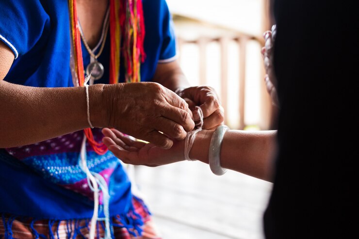 Una anciana no identificada de la minoría de la tribu étnica Karen une la muñeca de un invitado para bendecir en la ceremonia de vinculación