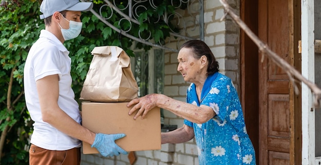 Anciana pagando el servicio de mensajería de la empresa de entrega de alimentos por pedido a través de la terminal. Concepto de epidemia.