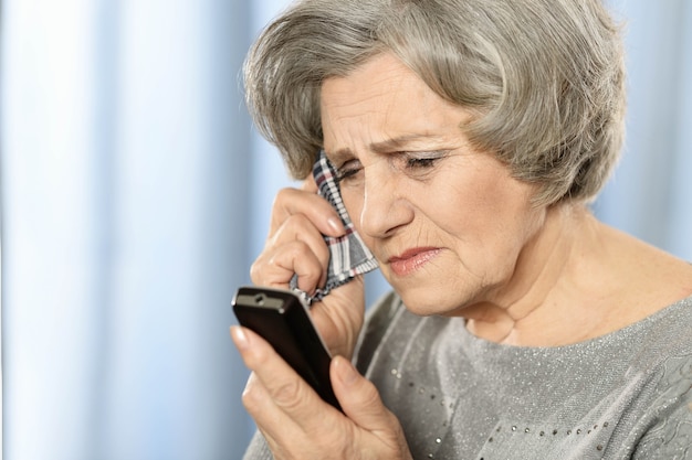 Anciana pensativa llamando por teléfono