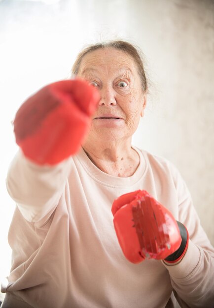 Una anciana de pie en guantes de boxeo rojos
