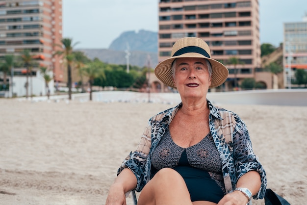 Anciana en la playa con un sombrero de paja