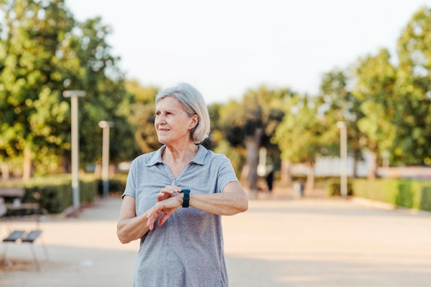 Anciana con un reloj deportivo mira hacia un lado en un parque