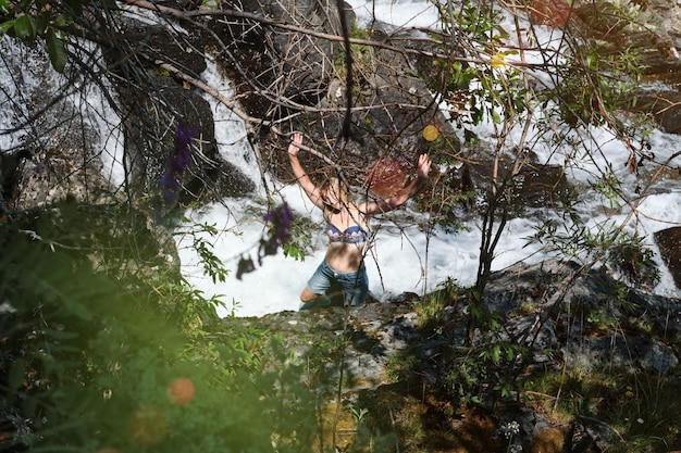 Anciana rubia se baña en una cascada en lo alto de las montañas