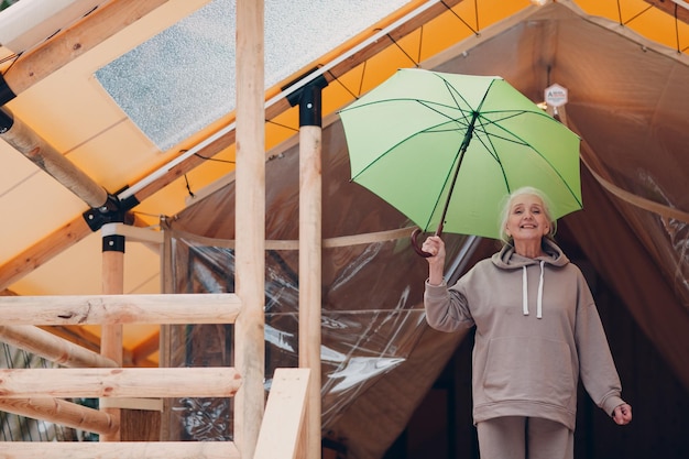 Anciana senior con paraguas en la tienda de campaña glamping Concepto moderno de estilo de vida de vacaciones