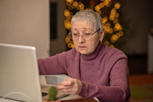 Una anciana sentada frente a una laptop se comunica en línea a través de las redes sociales.