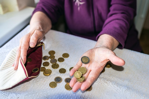 Foto una anciana sentada miserablemente en casa y contando las monedas restantes de la pensión