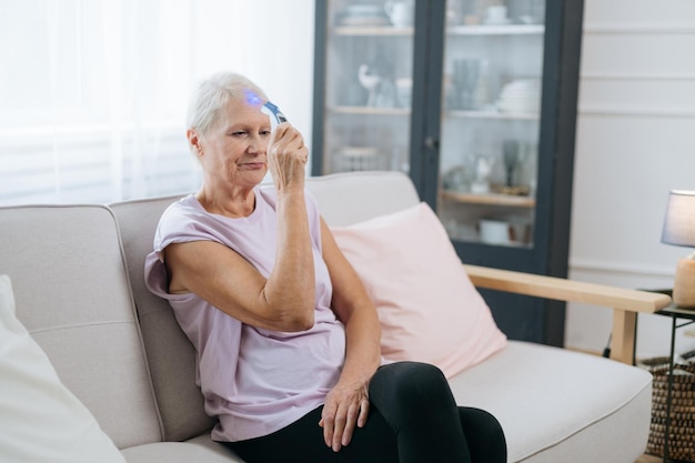 Anciana sentada en una pose de yoga frente a una computadora portátil abierta