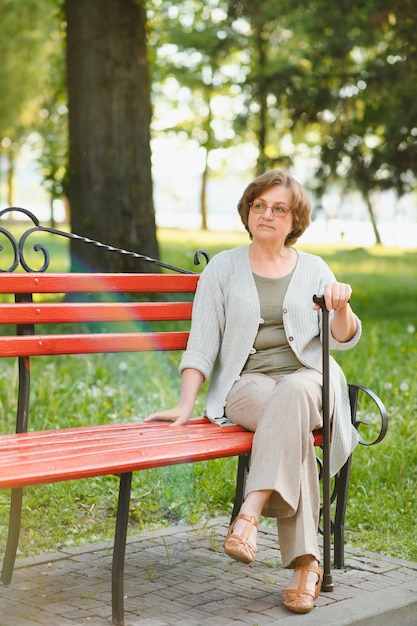 Anciana sentada y relajada en un banco al aire libre en el parque