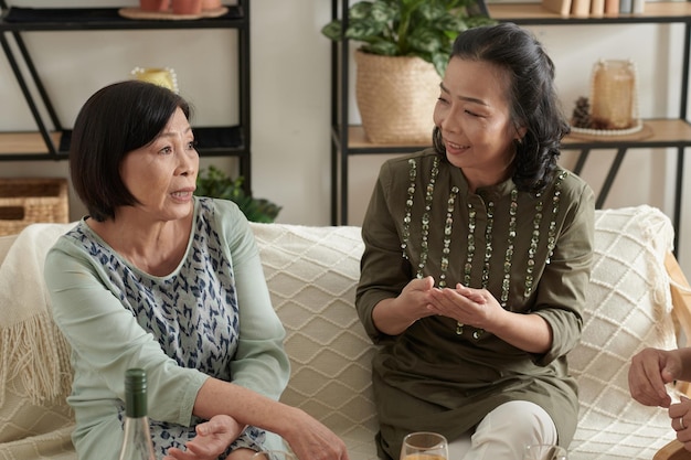 Una anciana seria discutiendo problemas con sus mejores amigos cuando beben vino en casa