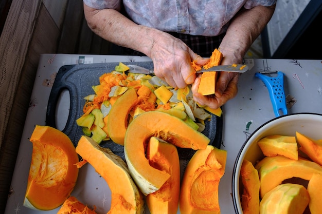 Foto anciana solitaria cortes y pastillas calabaza amarilla cocinar sopa de calabaza vida de retiro enfoque selectivo