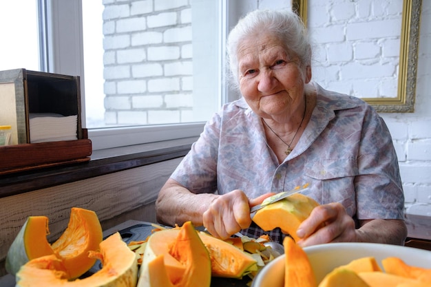 Anciana solitaria cortes y pastillas calabaza amarilla cocinar sopa de calabaza vida de retiro enfoque selectivo