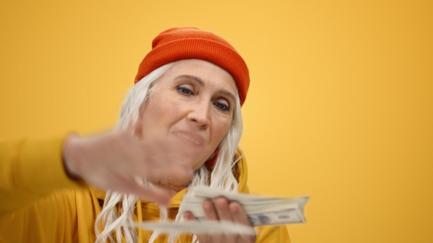 Una anciana con un sombrero naranja con un billete de un dólar en el medio.