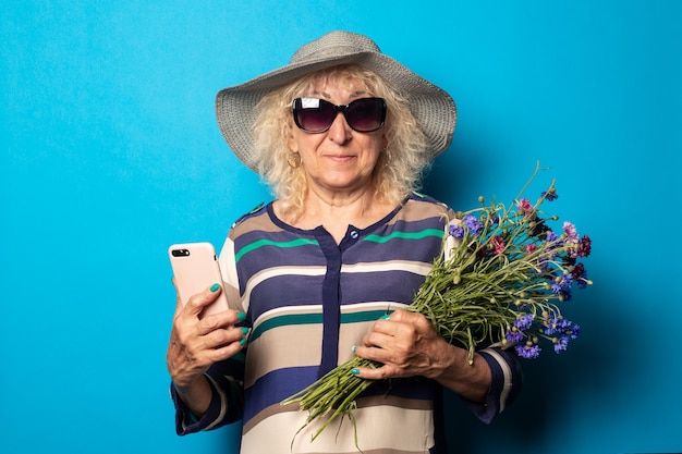 Anciana sonriente con ramo de flores sosteniendo teléfono