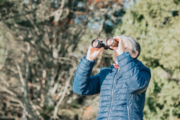 Anciana sonriente súper feliz aprendiendo a usar exploradores durante una caminata por la naturaleza, nuevo pasatiempo y hábito y actividades durante la tercera edad. Cuidado de la salud para personas mayores y naturaleza deporte abuela